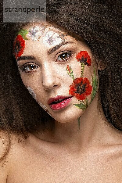 Schönes brünettes Mädchen mit Locken und einem Blumenmuster im Gesicht. Schönheit Blumen. Porträtaufnahme im Studio