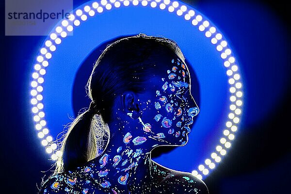 Porträt eines schönen Mädchens mit ultravioletter Farbe im Gesicht. Mädchen mit Neon-Make-up in Farbe Licht