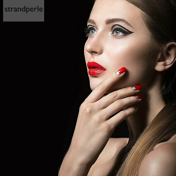 Schönes junges Mädchen mit einem hellen Make-up und roten Nägeln. Bild im Studio auf einem schwarzen Hintergrund aufgenommen