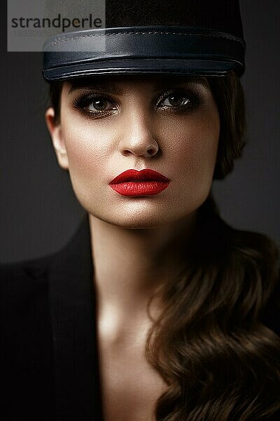 Schöne sexy Frau in einem modischen Hut  mit klassischem Make-up  Wellenhaar und roten Lippen. Schönes Gesicht. Foto im Studio aufgenommen