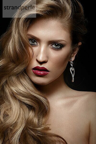 Schönes Mädchen mit roten Lippen und klassischem Make-up und Locken. Schönes Gesicht. Foto im Studio aufgenommen