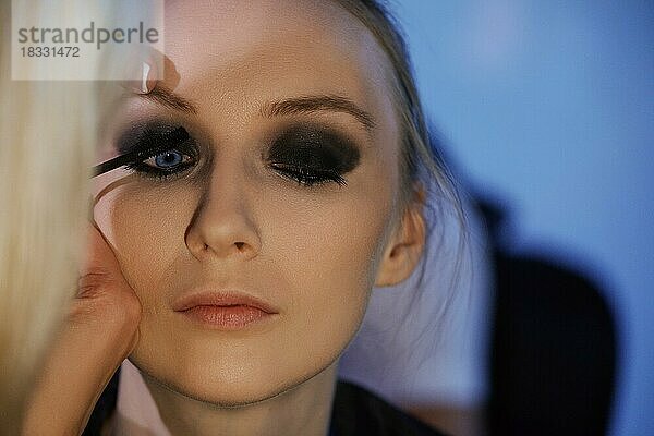 Weichzeichner Foto von Augen Make-up-Prozess. Maskenbildnerin trägt Lidschatten auf Modell auf