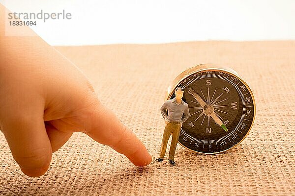 Figurine Mann neben einem Kompass auf Leinwand