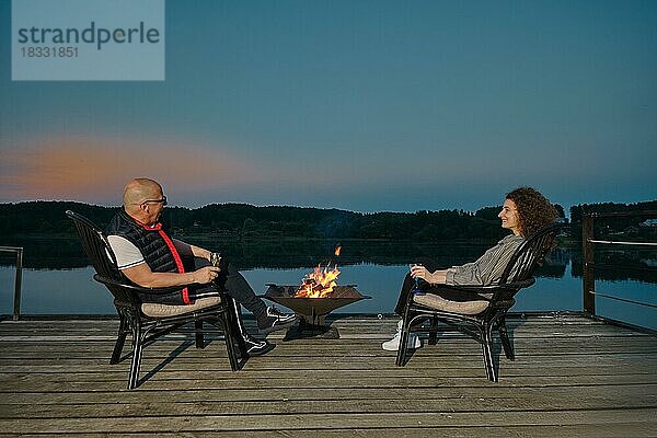 Ein Paar sitzt auf dem Steg neben dem Kamin und beobachtet den Sonnenuntergang