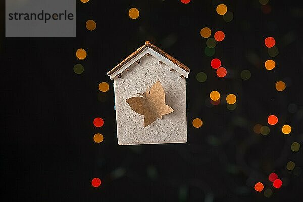 Papier Schmetterling auf einem Modell Haus auf einem Bokeh Licht