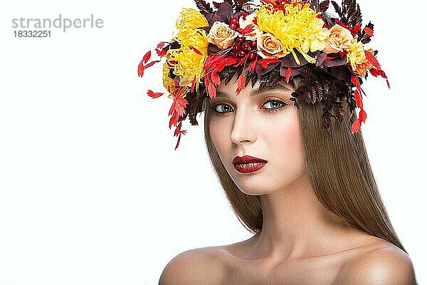 Schönes Mädchen mit hellem Herbstkranz aus Blättern und Blumen. Schönes Gesicht. Bild im Studio auf einem weißen Hintergrund genommen