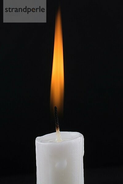 Brennende weiße Kerze auf schwarzem Hintergrund