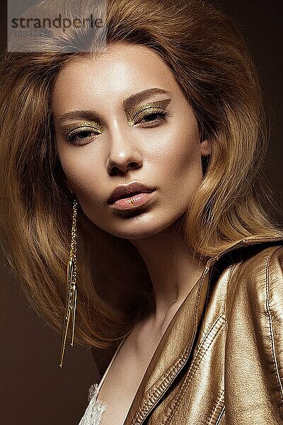 Schönes Mädchen in einem goldenen Kleid mit kreativen Make-up und Haar. Die Schönheit des Gesichts. Fotos im Studio geschossen
