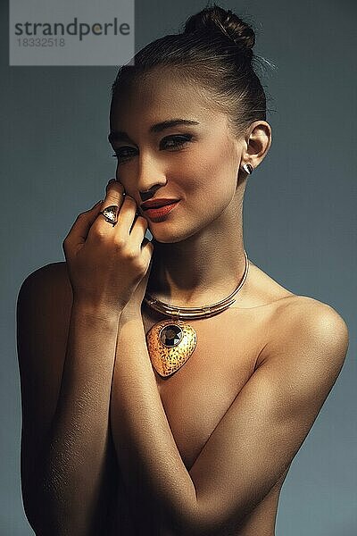 Dunkle und stimmungsvolle Foto von hübschen Modell mit großen goldenen Halskette