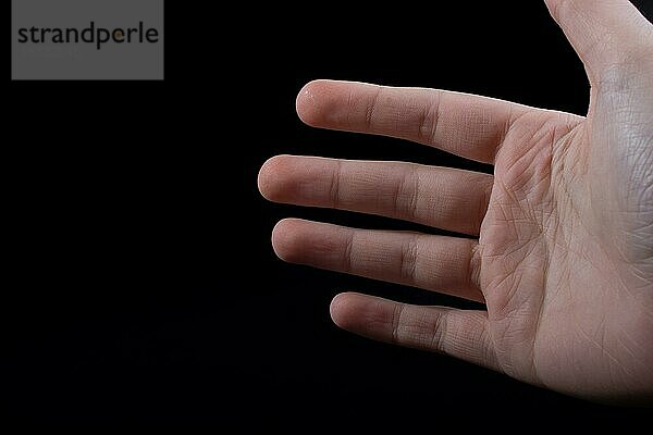 Vier Finger einer Kinderhand teilweise in schwarzem Hintergrund zu sehen