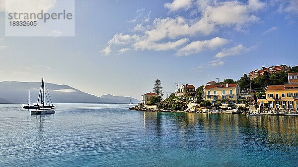 Ockerfarbene Häuser  Rote Ziegeldächer  Morgenlicht  blauer Himmel mit weißen Wolken  Hafenort  Fiskardo  Insel Kefalonia  Ionische Inseln  Griechenland  Europa