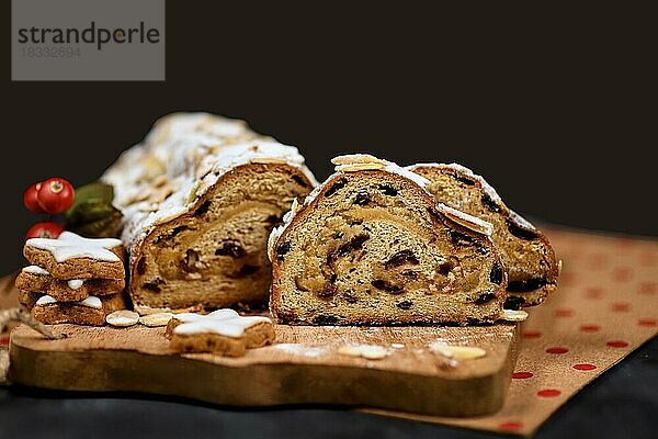 Scheiben von deutschem Stollen  einem Früchtebrot mit Nüssen  Gewürzen und getrockneten oder kandierten Früchten  bestreut mit Puderzucker  traditionell serviert in der Weihnachtszeit auf dunklem Hintergrund