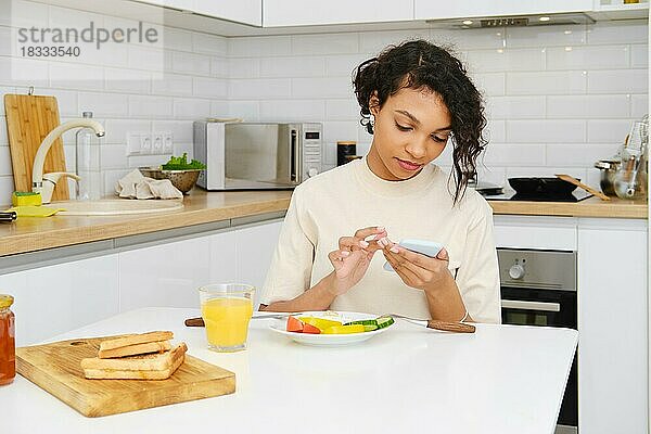 Junge afrikanische Frau liest morgens beim Frühstück eine Nachricht auf dem Handy