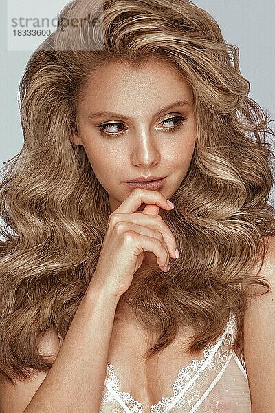 Schönes blondes Mädchen mit perfekt gelocktem Haar und klassischem Make-up. Schönheit Gesicht und Haar. Bild im Studio aufgenommen