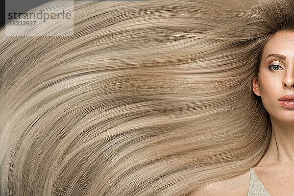 Schönes blondes Mädchen in Bewegung mit einem perfekt glatten Haar  und klassisches Make-up. Schönes Gesicht. Bild im Studio aufgenommen