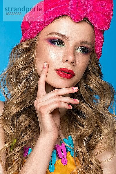 Helles  fröhliches Mädchen mit einem Hut  buntem Make-up  Locken und rosa Maniküre. Schönes Gesicht. Foto im Studio aufgenommen