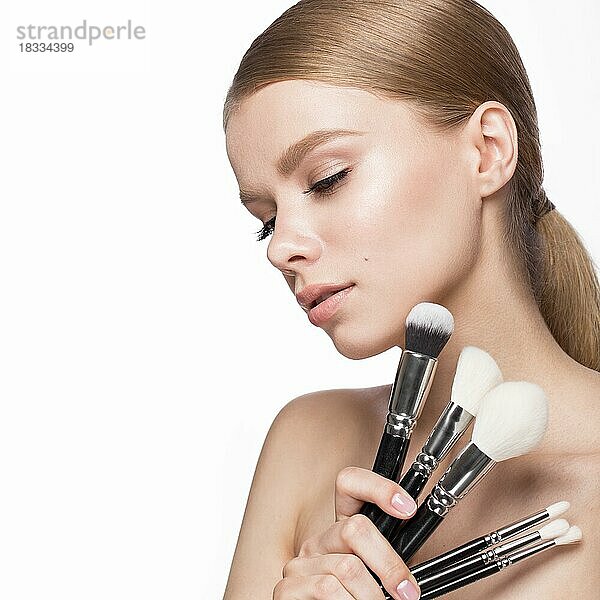 Schönes junges Mädchen mit einem leichten Natur-Make-up  Pinsel für Kosmetik und Französisch Maniküre. Schönes Gesicht. Bild im Studio auf einem weißen Hintergrund genommen