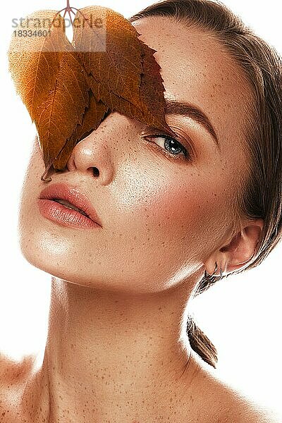 Schönes Mädchen mit nacktem klassischen Make-up und hellem Herbstlaub. Schönheit Gesicht. Bild im Studio auf einem weißen Hintergrund genommen