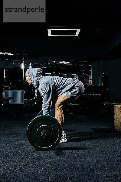 Muskulöser Mann beim Kreuzheben mit einer Langhantel im Fitnessstudio  Seitenansicht