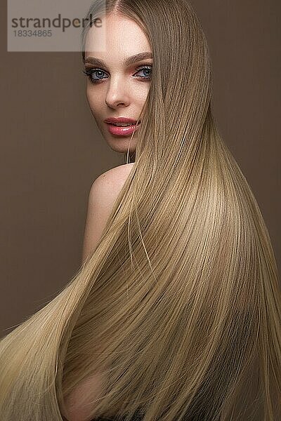 Schönes blondes Mädchen mit einem perfekt glatten Haar  klassisches Make-up. Schönes Gesicht. Bild im Studio auf einem weißen Hintergrund genommen