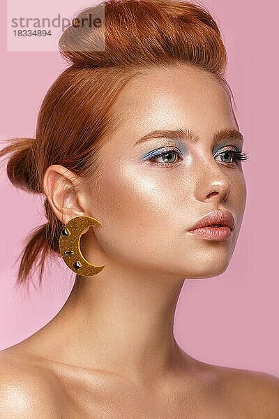 Schönes Mädchen mit ungewöhnlichen Accessoires und Make-up auf einem hellen Hintergrund. Schönes Gesicht. Foto im Studio aufgenommen