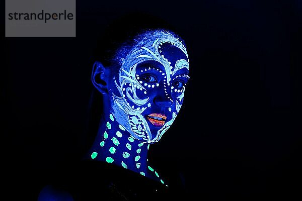 Porträt eines schönen Mädchens mit ultravioletter Farbe im Gesicht. Mädchen mit Neon-Make-up in Farbe Licht