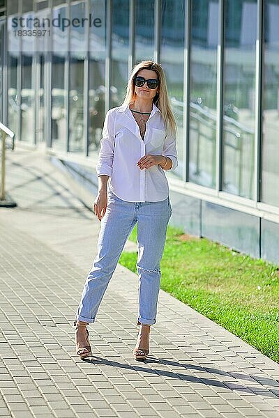 Streetstyle-Mode  Dame in weißem Hemd und Boyfriend-Jeans beim Spaziergang im Geschäftszentrum