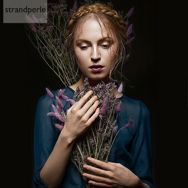 Schönes Mädchen mit einem sanften Make-up und Frisur in Form von Zöpfen  trockene Blumen in ihren Händen. Schönes Gesicht. Bild im Studio aufgenommen