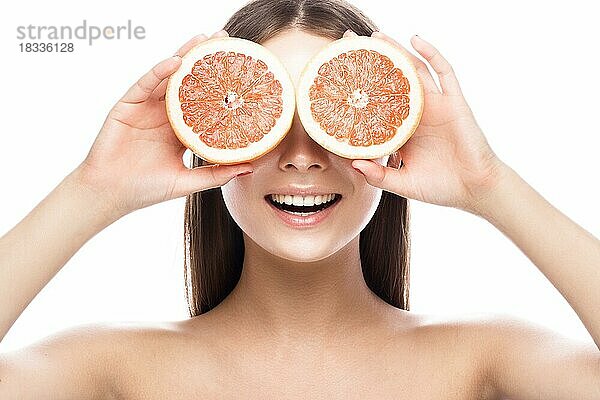 Schönes junges Mädchen mit einem leichten natürlichen Make-up und perfekter Haut mit Grapefruit in der Hand. Schönes Gesicht. Bild im Studio auf einem weißen Hintergrund aufgenommen