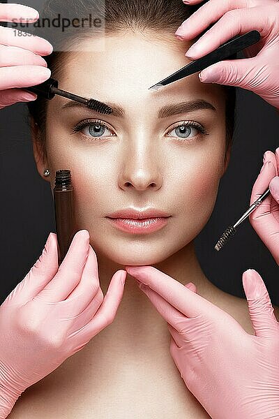 Schönes junges Mädchen mit natürlichen nackt Make-up mit kosmetischen Werkzeugen in den Händen. Schönes Gesicht. Foto im Studio aufgenommen