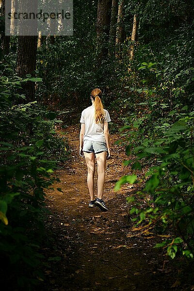 Eine junge Frau wandert auf einem Waldweg
