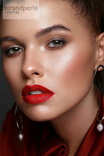 Schönes frisches Mädchen mit klassischem Make-up  glatten Haaren in einem roten Kleid. Schönes Gesicht. Foto im Studio aufgenommen