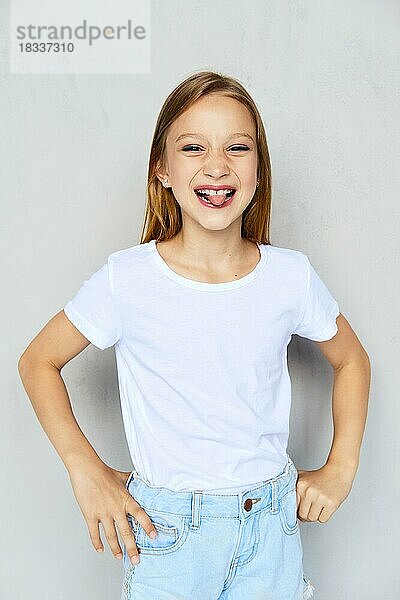 Junges sportliches Mädchen in weißem T-Shirt streckt die Zunge heraus