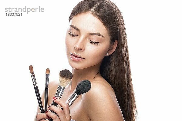 Schönes junges Mädchen mit einem leichten natürlichen Make-up  Pinsel für Kosmetik und perfekte Haut. Schönheit Gesicht. Bild im Studio auf einem weißen Hintergrund genommen