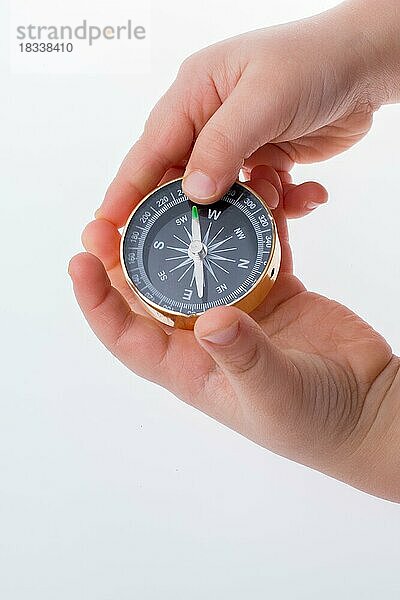 Kinderhand hält einen Kompass auf weißem Hintergrund
