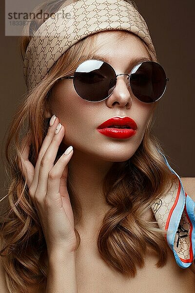 Schönes Mädchen in stilvoller Kleidung mit Sonnenbrille und roten sexy Lippen. Schönes Gesicht. Foto im Studio aufgenommen