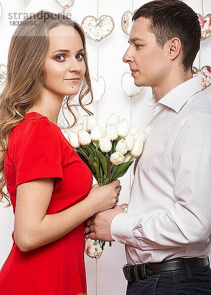 Schönes junges verliebtes Paar mit einem Blumenstrauß. Valentinstag. Bild im Studio aufgenommen
