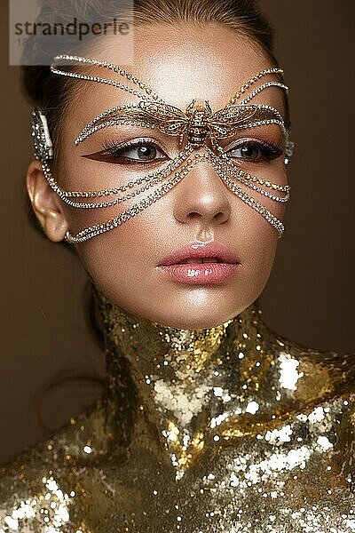 Schönes Mädchen in einer goldenen Maske und hellem Abend-Make-up. Schönes Gesicht. Foto im Studio aufgenommen