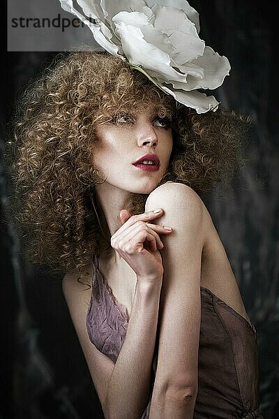 Schönes Mädchen mit lockigem Haar in Dessous mit großer Blume. Die Schönheit des Gesichts. Fotos im Studio geschossen