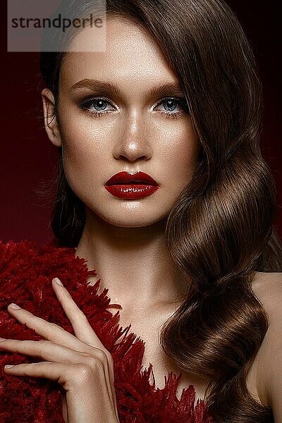 Ein schönes Mädchen mit Abend-Make-up  einer Lockenwelle und roten Lippen. Schönes Gesicht. Foto im Studio aufgenommen