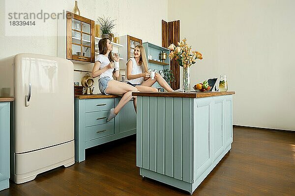 Zwei junge attraktive Frauen trinken Tee und unterhalten sich in der Küche