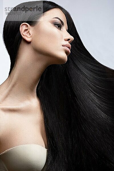 Schönes brünettes Mädchen in Bewegung mit einem perfekt glatten Haar  und klassisches Make-up. Schönheit Gesicht. Bild im Studio auf einem weißen Hintergrund genommen