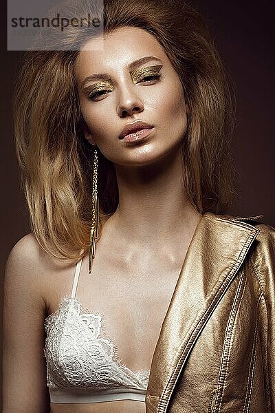 Schönes Mädchen in einem goldenen Kleid mit kreativen Make-up und Haar. Die Schönheit des Gesichts. Fotos im Studio geschossen