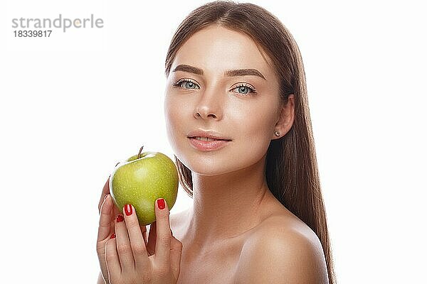 Schönes junges Mädchen mit einem leichten natürlichen Make-up und perfekter Haut mit Apfel in der Hand. Schönes Gesicht. Bild im Studio auf einem weißen Hintergrund genommen