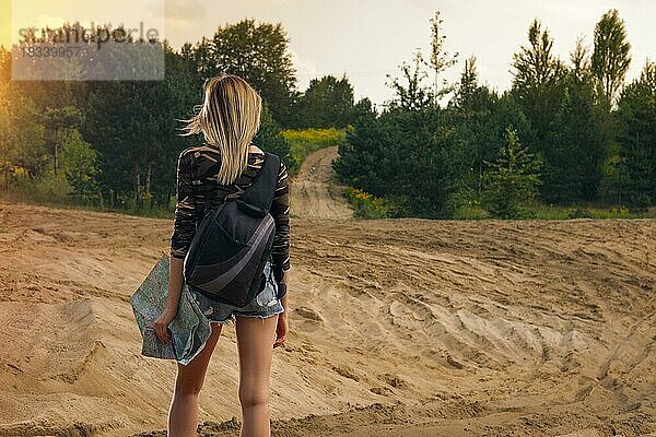Rückseite eines reisenden Mädchens auf der Suche nach der richtigen Richtung auf einer Karte am Waldrand
