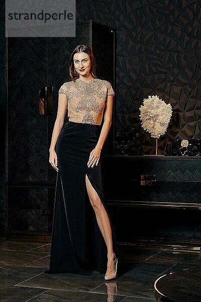 Unauffälliges Foto eines Modemodells  das in einem Kleid mit Spitzenoberteil und tiefem Ausschnitt posiert