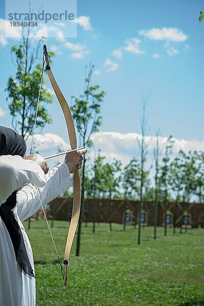 Bogenschütze mit Bogen in traditioneller Kleidung schießt einen Pfeil