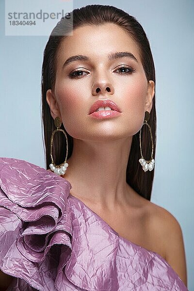 Schönes frisches Mädchen mit klassischem Make-up  glatten Haaren in einem lila Kleid. Schönes Gesicht. Foto im Studio aufgenommen