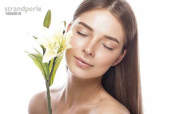 Schönes junges Mädchen mit einem leichten natürlichen Make-up und perfekter Haut mit Blumen in der Hand. Schönes Gesicht. Bild im Studio auf einem weißen Hintergrund aufgenommen