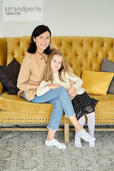 Lifestyle-Foto von Mutter und Tochter zu Hause auf dem Sofa